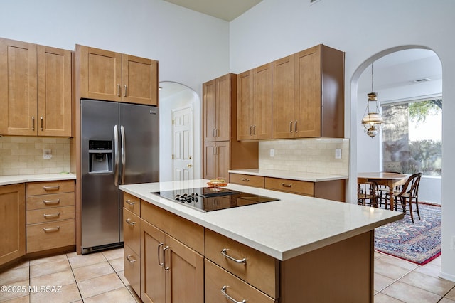 10380 E Rancho Del Este Dr, Tucson, AZ 85749 - kitchen with stainless steel fridge with ice dispenser, black electric cooktop, arched walkways, light tile patterned floors, and light countertops