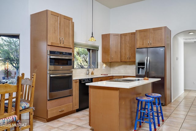 10380 E Rancho Del Este Dr, Tucson, AZ 85749 - kitchen featuring black appliances, decorative backsplash, light tile patterned floors, light countertops, and a center island