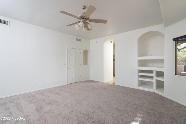 10380 E Rancho Del Este Dr, Tucson, AZ 85749 - carpeted empty room featuring built in shelves, ceiling fan, and arched walkways