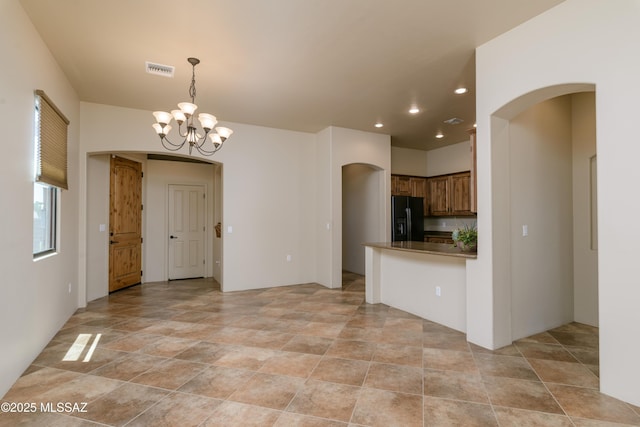 341 E Calderwood Rd, Tucson, AZ 85704 - kitchen featuring black refrigerator with ice dispenser, arched walkways, a chandelier, dark countertops, and brown cabinetry