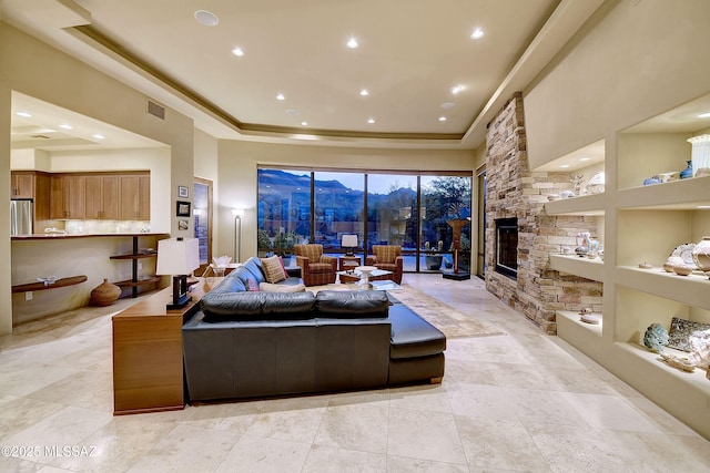 5254 W Saguaro Cliffs Dr, Tucson, AZ 85745 - living room with a tray ceiling, a mountain view, recessed lighting, a stone fireplace, and built in shelves