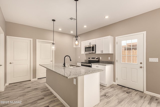 3710 S Bellingham Pl, Tucson, AZ 85730 - kitchen with stainless steel appliances, light wood-type flooring, white cabinetry, a kitchen island with sink, and light stone counters