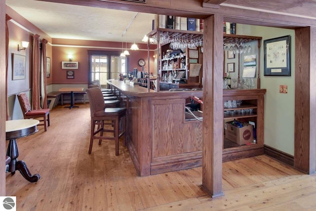 bar with hanging light fixtures and light hardwood / wood-style floors