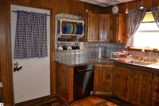 kitchen featuring dark hardwood / wood-style floors, wooden walls, sink, dishwasher, and backsplash