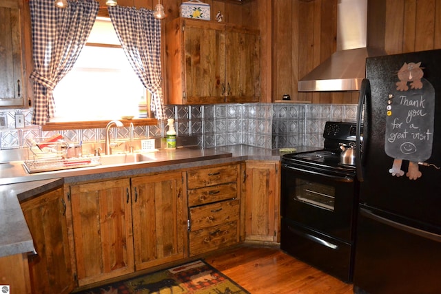 kitchen with wall chimney range hood, dark hardwood / wood-style floors, backsplash, and black appliances