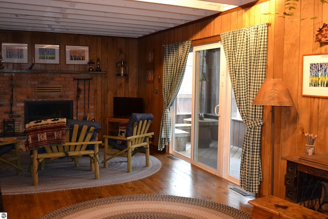 living room featuring dark hardwood / wood-style floors, a brick fireplace, and wooden walls