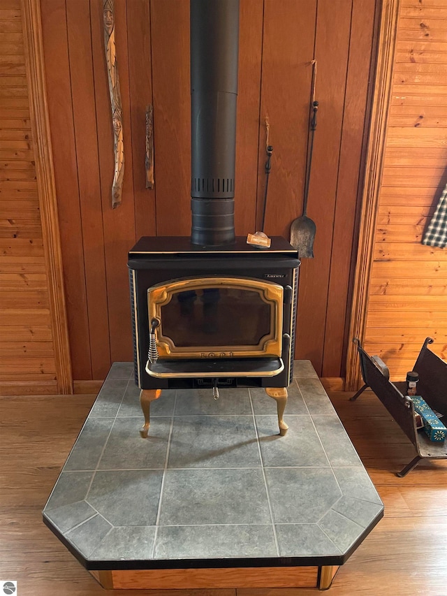 room details featuring wood walls, a wood stove, and light hardwood / wood-style floors