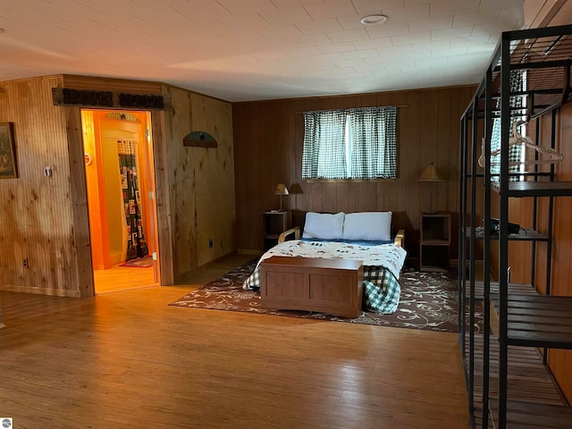 bedroom featuring light hardwood / wood-style flooring and wooden walls