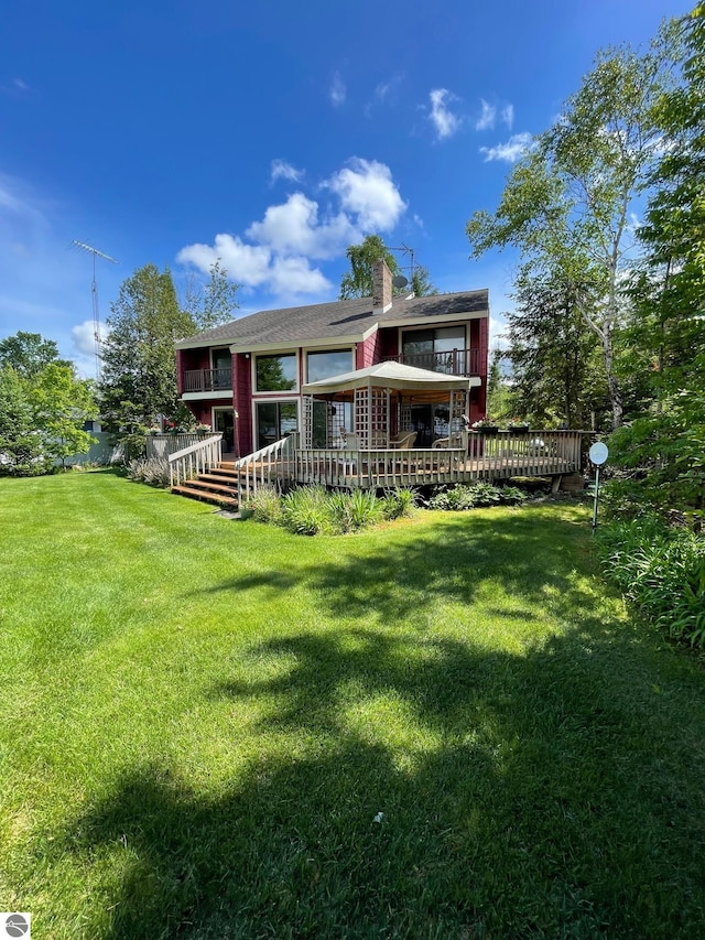 rear view of house with a wooden deck and a lawn