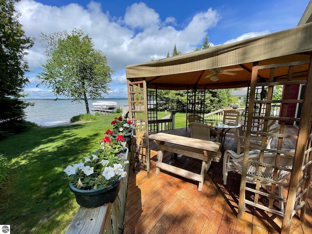 deck featuring a gazebo, a water view, a yard, and ceiling fan