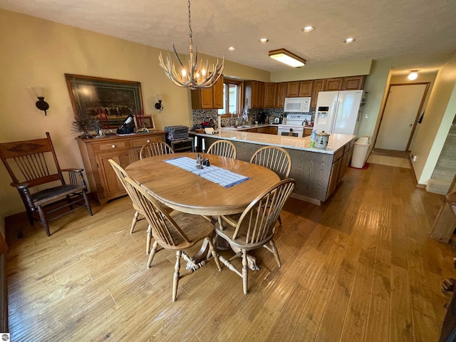 dining space with an inviting chandelier, sink, and light hardwood / wood-style floors