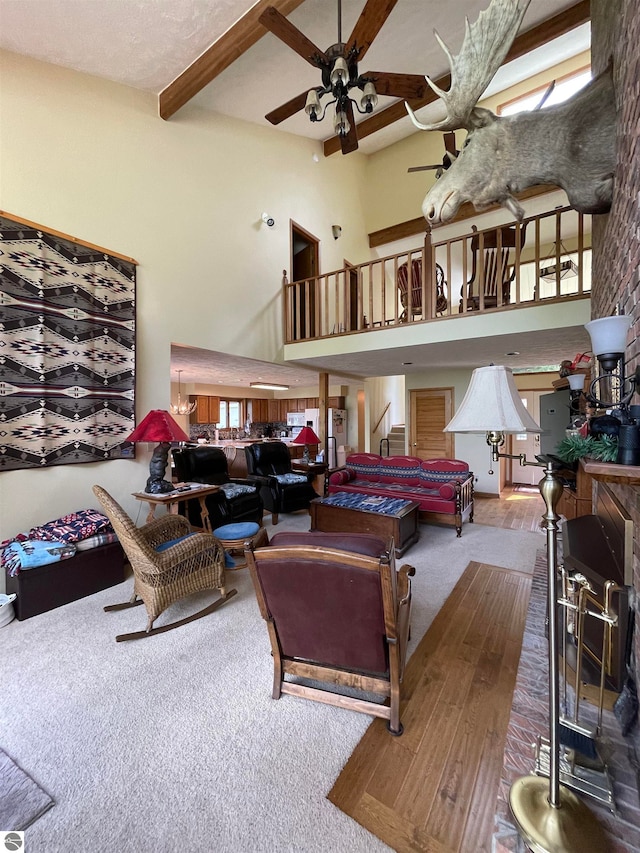 living room with a high ceiling, hardwood / wood-style floors, ceiling fan, and beam ceiling