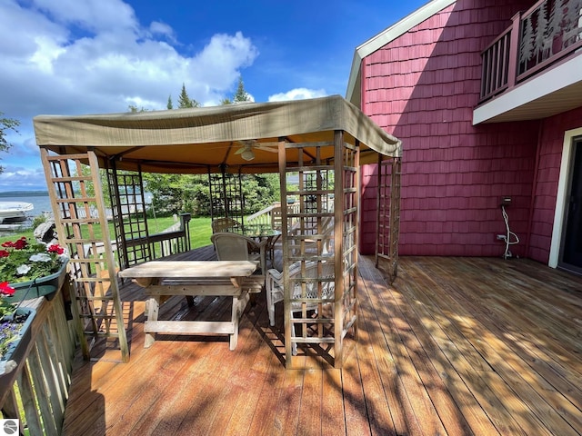 wooden terrace with ceiling fan and a water view