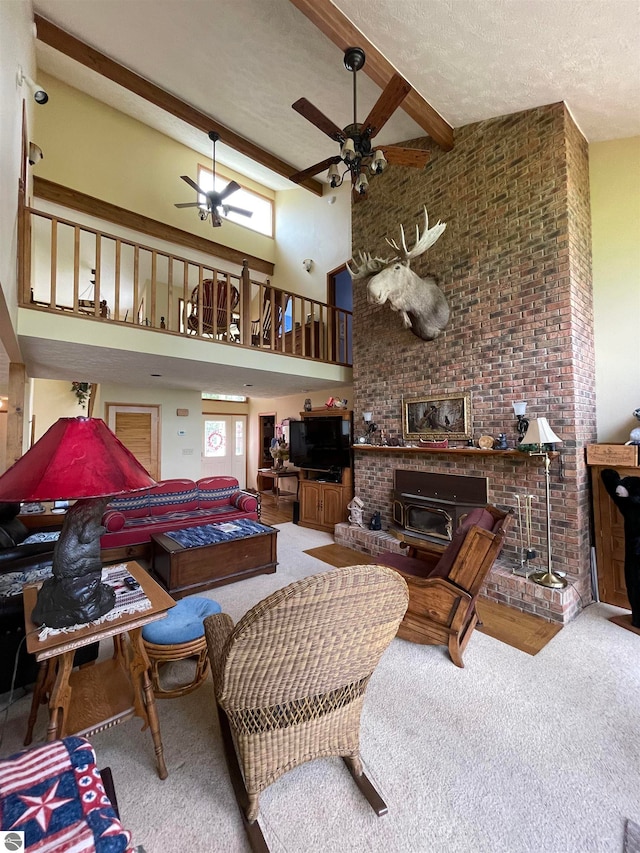 carpeted living room featuring ceiling fan, beamed ceiling, a fireplace, high vaulted ceiling, and a textured ceiling