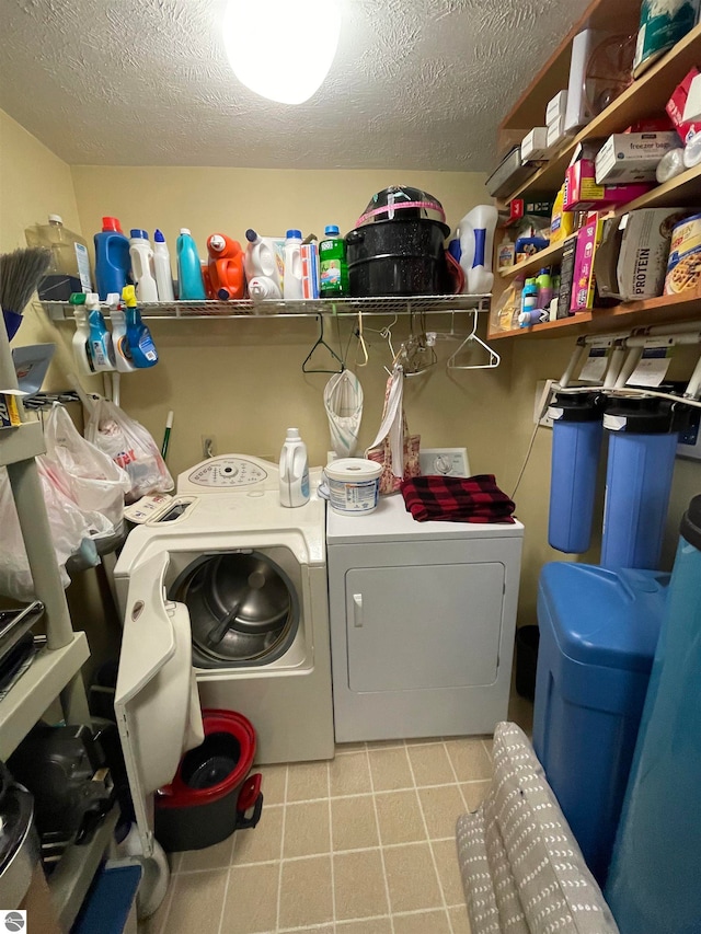 laundry room with a textured ceiling, light tile flooring, and washing machine and dryer