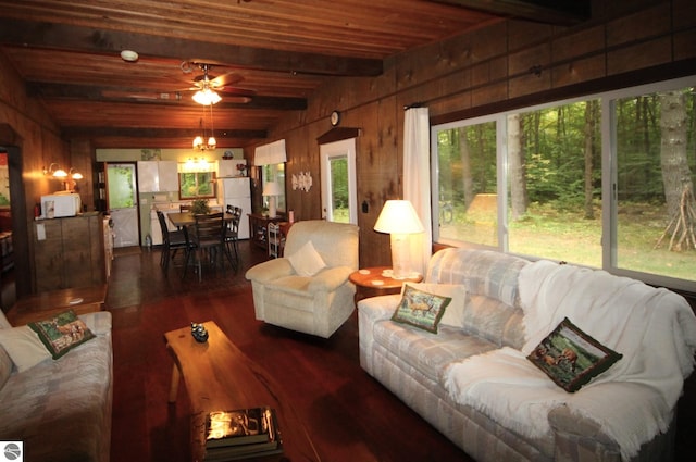 living room with wooden walls, ceiling fan with notable chandelier, dark hardwood / wood-style floors, and lofted ceiling with beams