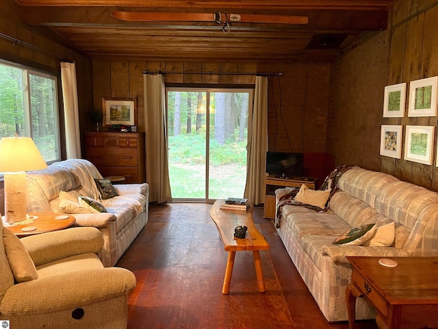 living room featuring wooden walls, beam ceiling, and wood ceiling