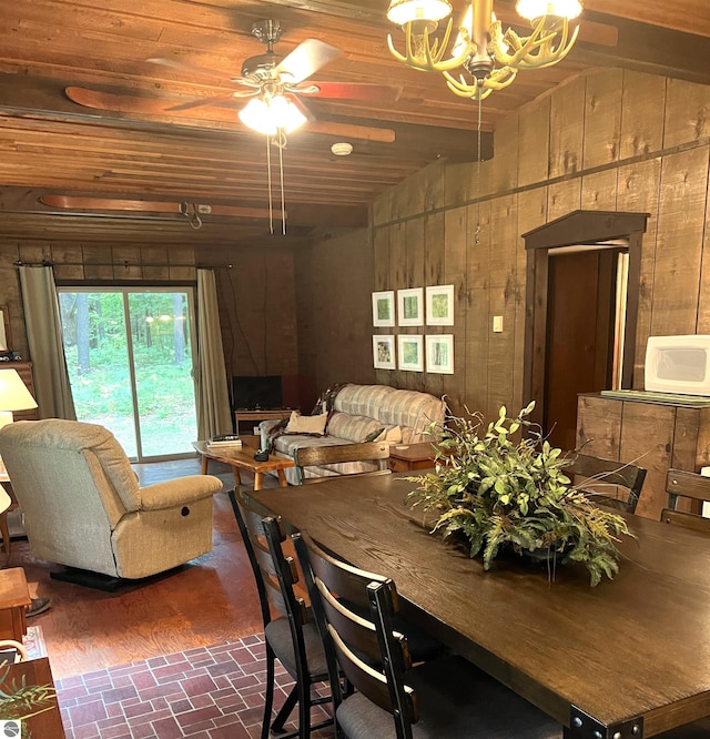 dining area with wooden walls, ceiling fan with notable chandelier, and wooden ceiling