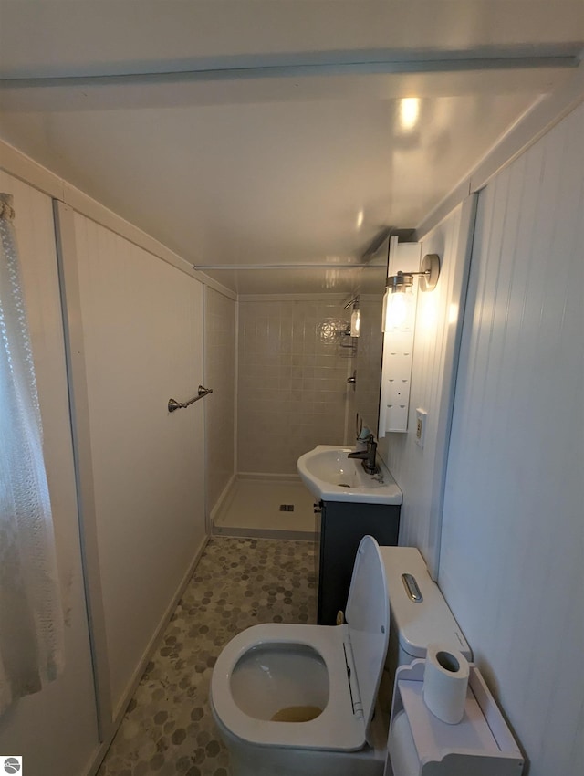 bathroom with toilet, tile floors, vanity, and tiled shower