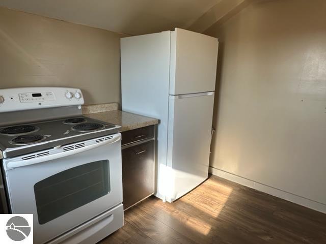 kitchen with white appliances, white cabinetry, dark wood-type flooring, and light stone countertops