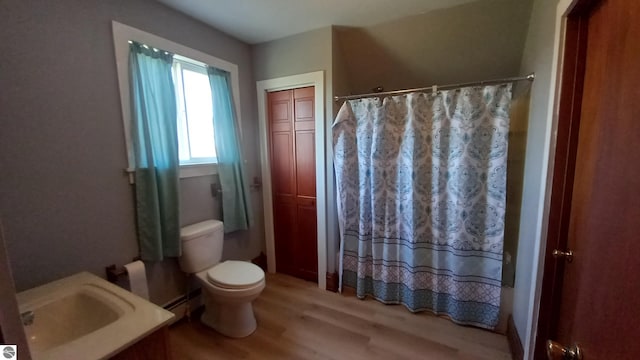 bathroom featuring hardwood / wood-style flooring, baseboard heating, and toilet