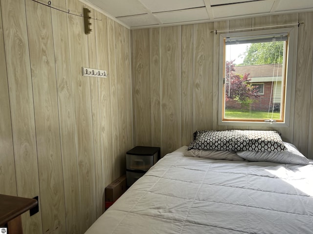 bedroom with a paneled ceiling and wood walls