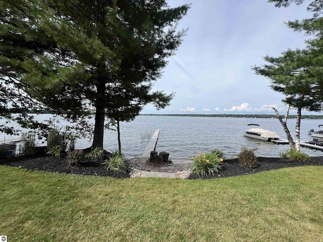 view of dock with a water view and a lawn