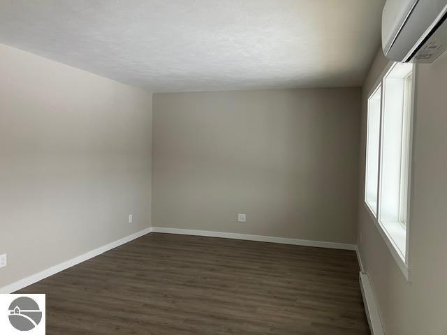 spare room with a wall mounted air conditioner and hardwood / wood-style floors