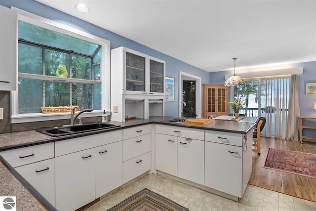 kitchen with decorative light fixtures, white cabinetry, light tile floors, and sink