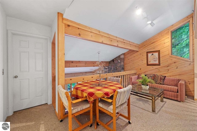 carpeted dining area with lofted ceiling with beams and wooden walls