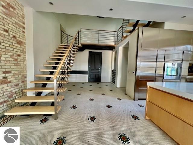 tiled entryway featuring brick wall and a high ceiling