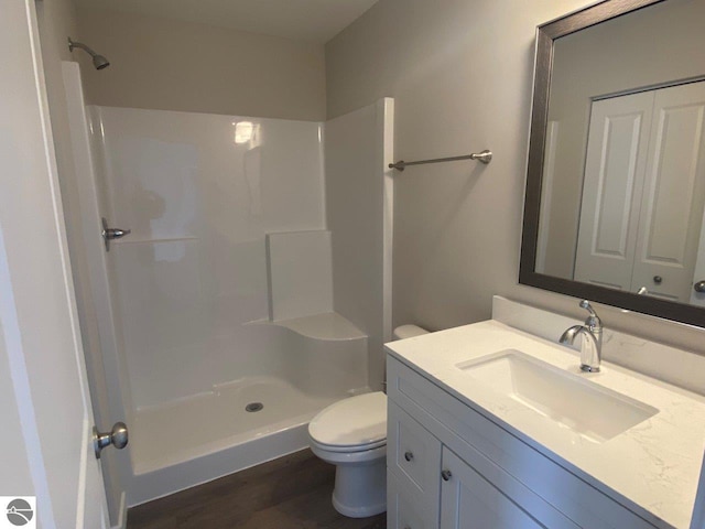 bathroom featuring a shower, toilet, hardwood / wood-style flooring, and vanity with extensive cabinet space