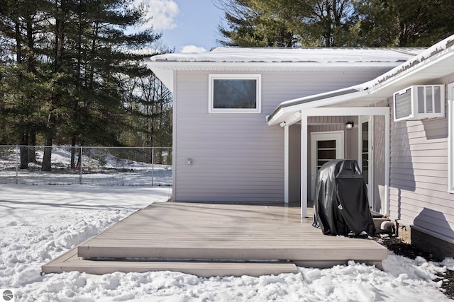 snow covered deck with a wall mounted air conditioner and grilling area