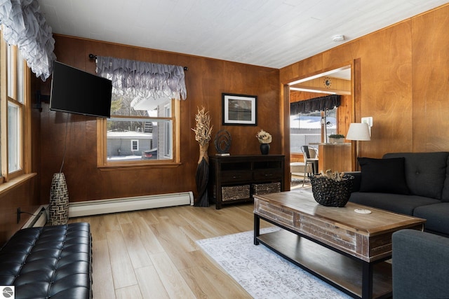 living room with wood walls, light hardwood / wood-style floors, and a baseboard radiator