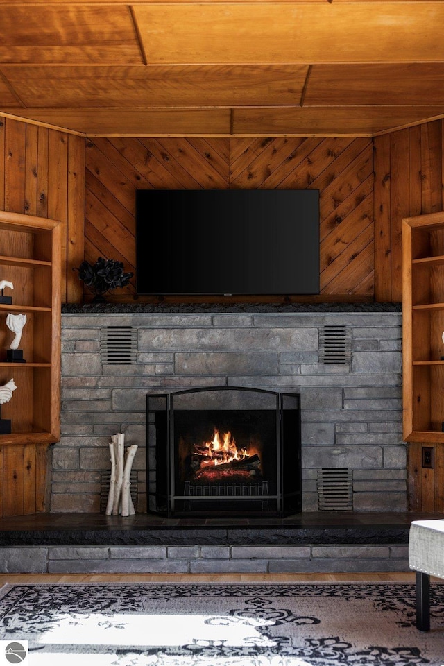 room details with wood ceiling, a stone fireplace, and wood walls