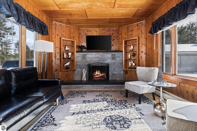 living room featuring wooden ceiling, a fireplace, wood walls, and a baseboard radiator