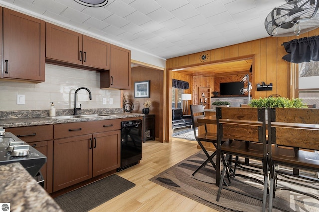 kitchen with wooden walls, light hardwood / wood-style flooring, backsplash, sink, and dishwasher