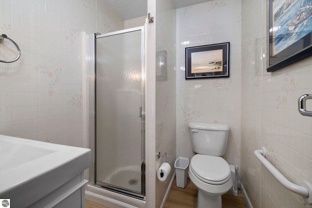 bathroom featuring tile walls, walk in shower, toilet, vanity, and hardwood / wood-style flooring