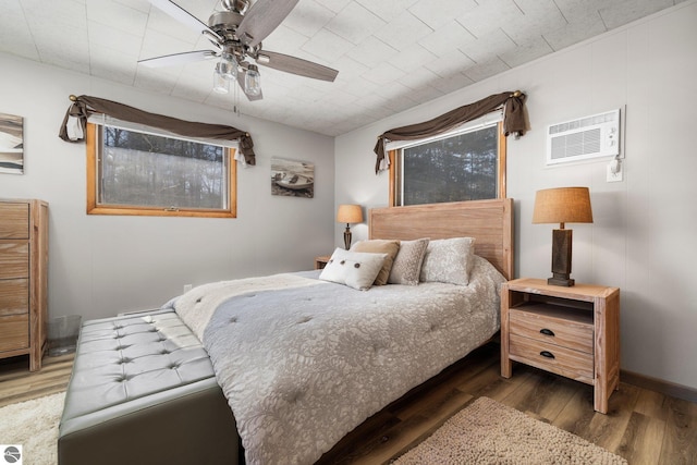 bedroom featuring dark hardwood / wood-style flooring, ceiling fan, and a wall mounted AC