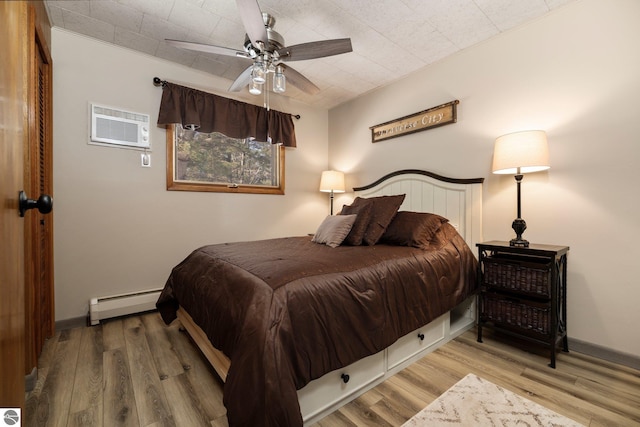 bedroom featuring a wall mounted AC, ceiling fan, light hardwood / wood-style floors, and a baseboard heating unit