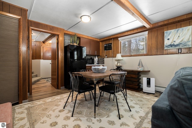 dining area with wood walls, light hardwood / wood-style flooring, and baseboard heating