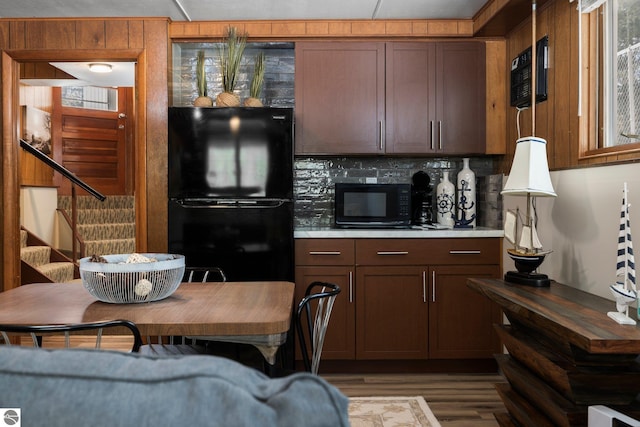 kitchen featuring backsplash, a wall mounted AC, dark hardwood / wood-style flooring, and black appliances