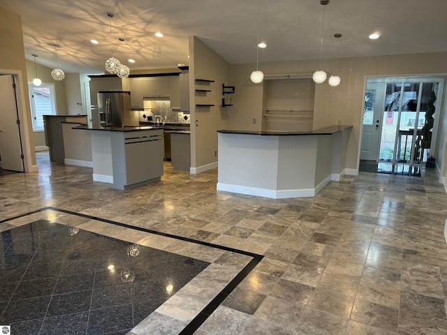 kitchen with decorative light fixtures, decorative backsplash, stainless steel fridge with ice dispenser, and a kitchen island with sink