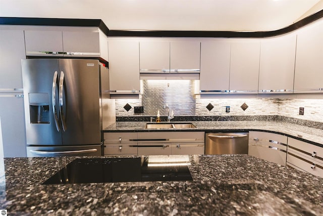 kitchen featuring white cabinets, sink, stainless steel appliances, and dark stone counters