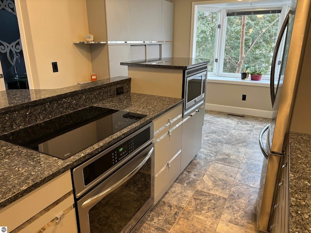 kitchen featuring dark stone countertops, white cabinetry, and stainless steel appliances