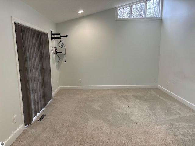 carpeted spare room featuring lofted ceiling