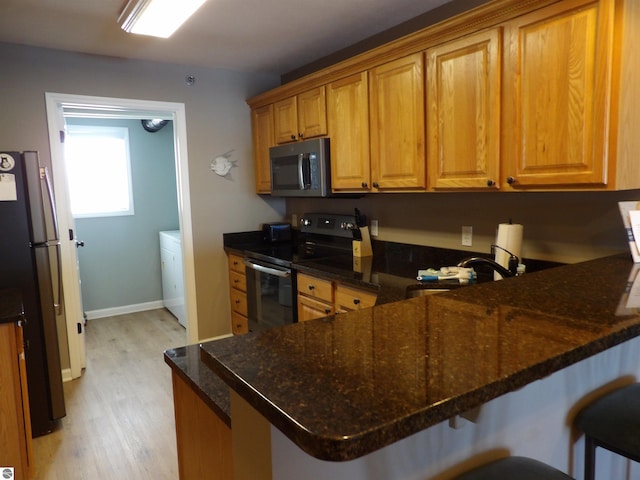 kitchen featuring a breakfast bar area, light wood-type flooring, stainless steel appliances, and kitchen peninsula