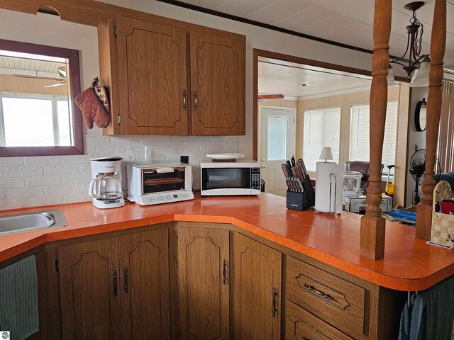 5934 Chippewa Trl, Hale, MI 48739 - kitchen featuring brown cabinetry, light countertops, decorative backsplash, and white microwave