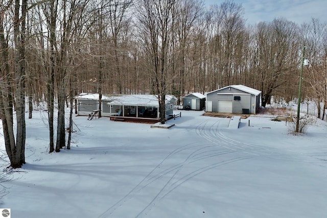 yard covered in snow featuring a garage and an outdoor structure