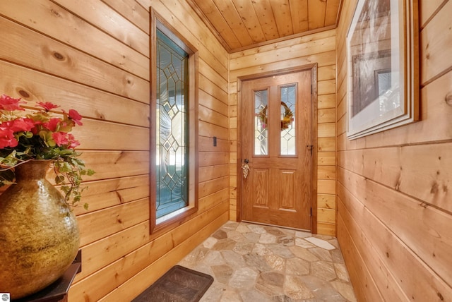 entryway with wood walls, wooden ceiling, light tile patterned floors, and a wealth of natural light